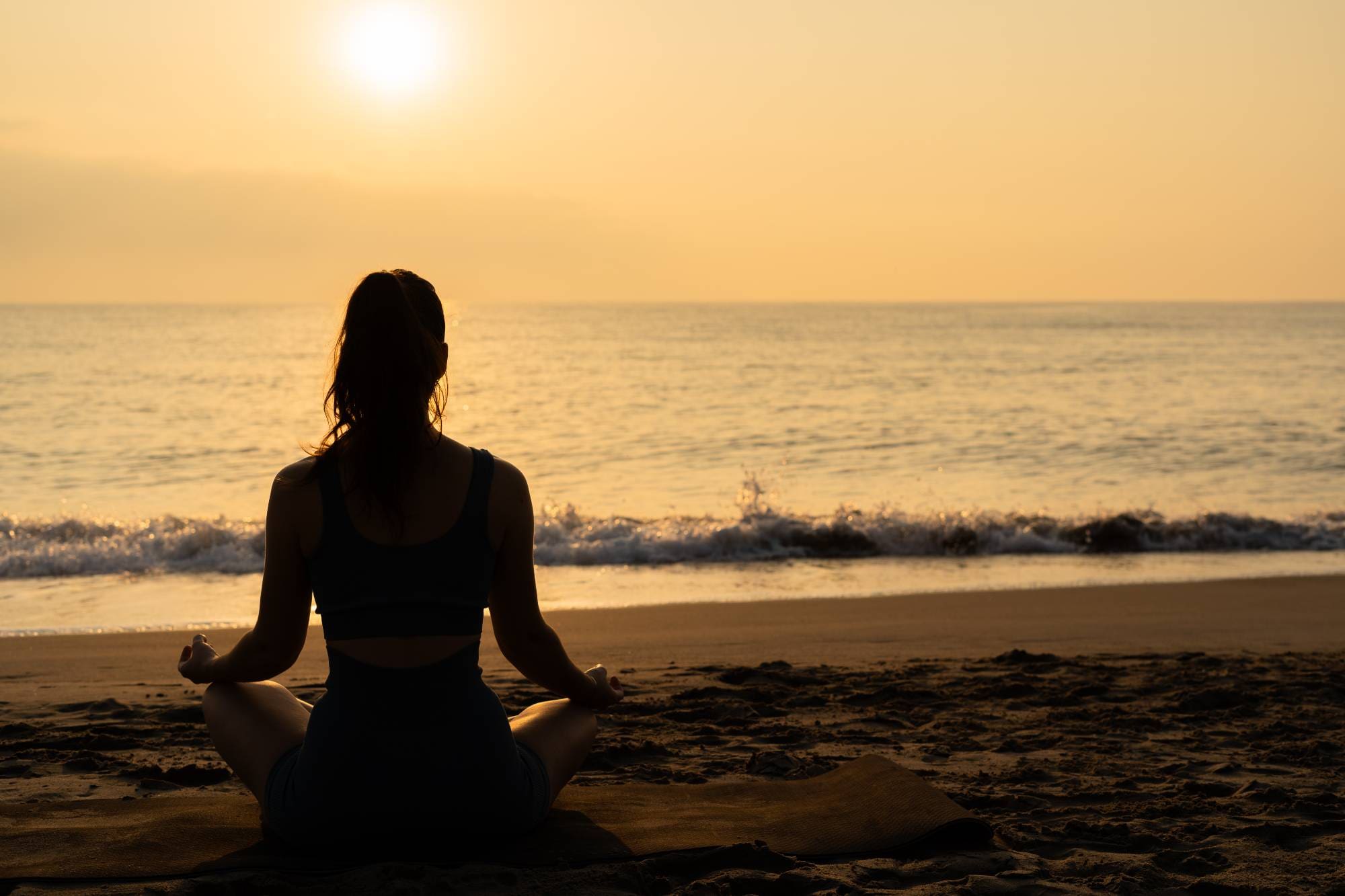A woman sitting on the beach in front of the ocean.