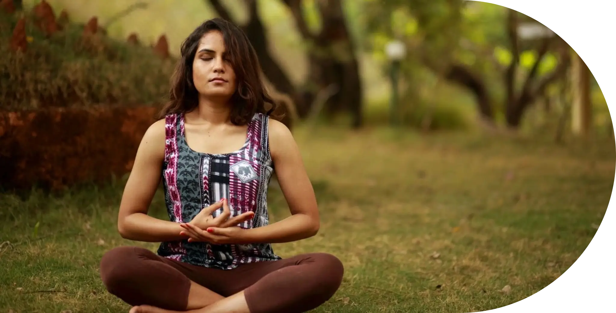 A woman sitting in the grass with her hands folded together.