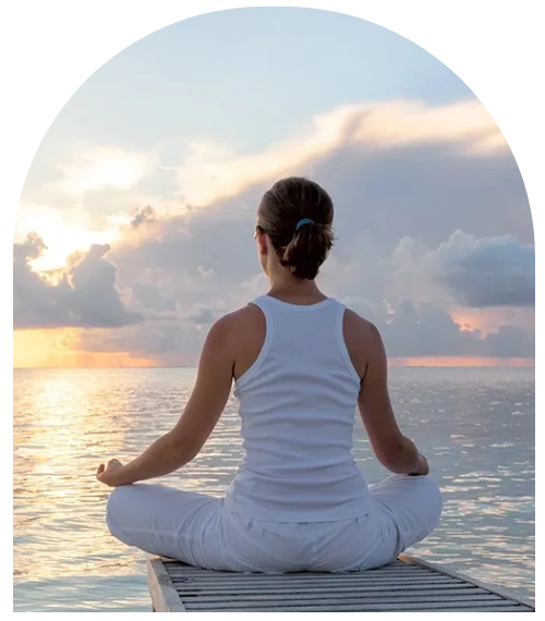 A woman sitting in the ocean doing yoga.