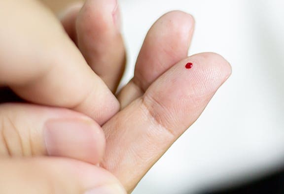 Finger with a blood drop on tip.