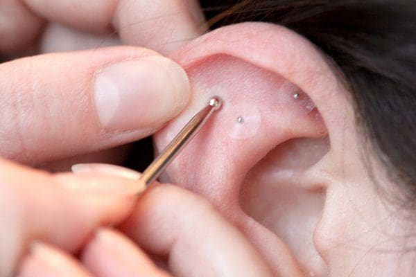 Piercing ear with a metal tool.