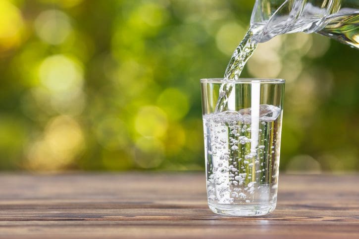 Pouring water into a glass, outdoor setting.