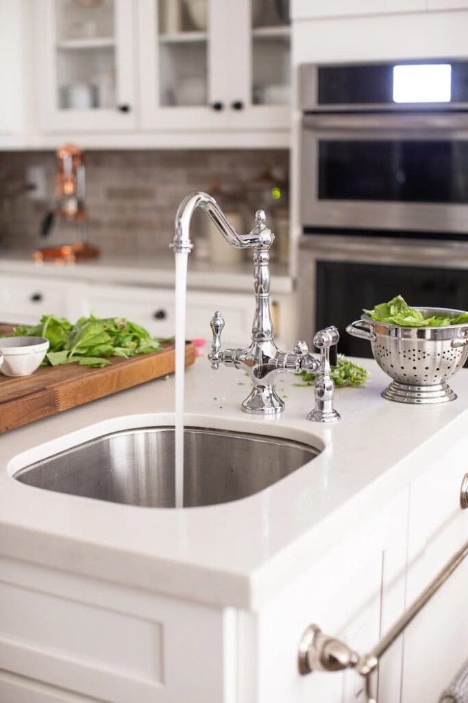 Kitchen sink with running water and vegetables.