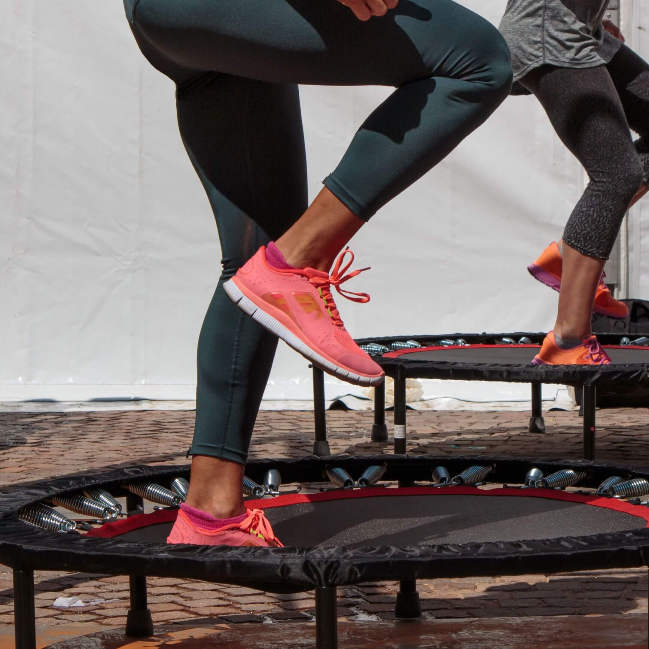 People exercising on mini trampolines outdoors.