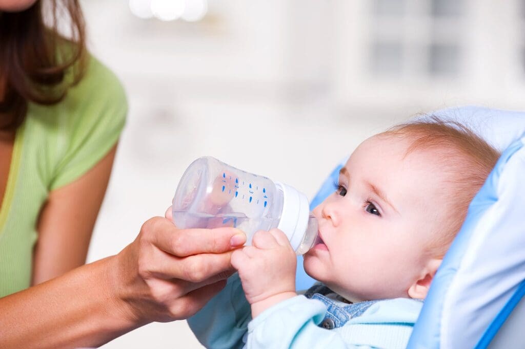 Baby drinking from a bottle in stroller.