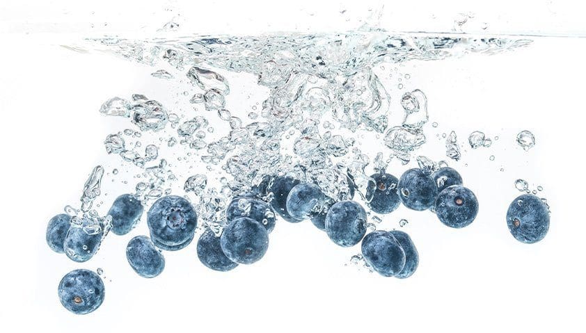 Blueberries splashing into clear water.