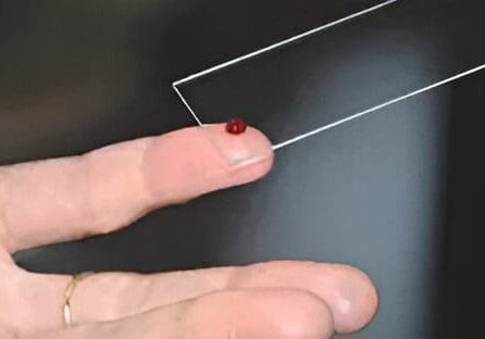 A person holding a wire with a red dot on it.